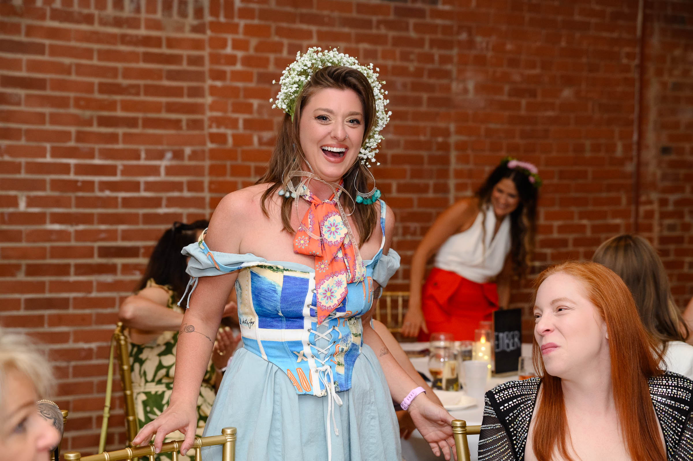 A wearable-art model moving through guests seated at an ArtPop x The Pinnacle Dinner table